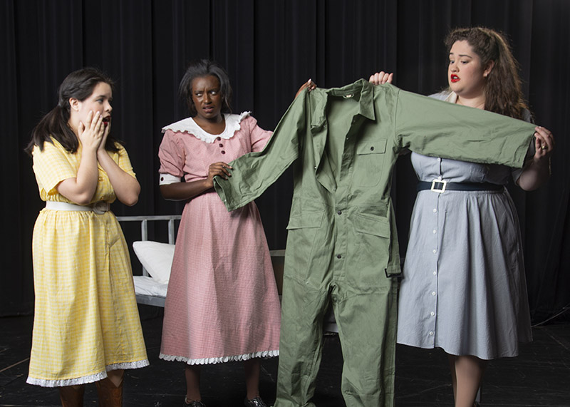 three women holding up green jumpsuit